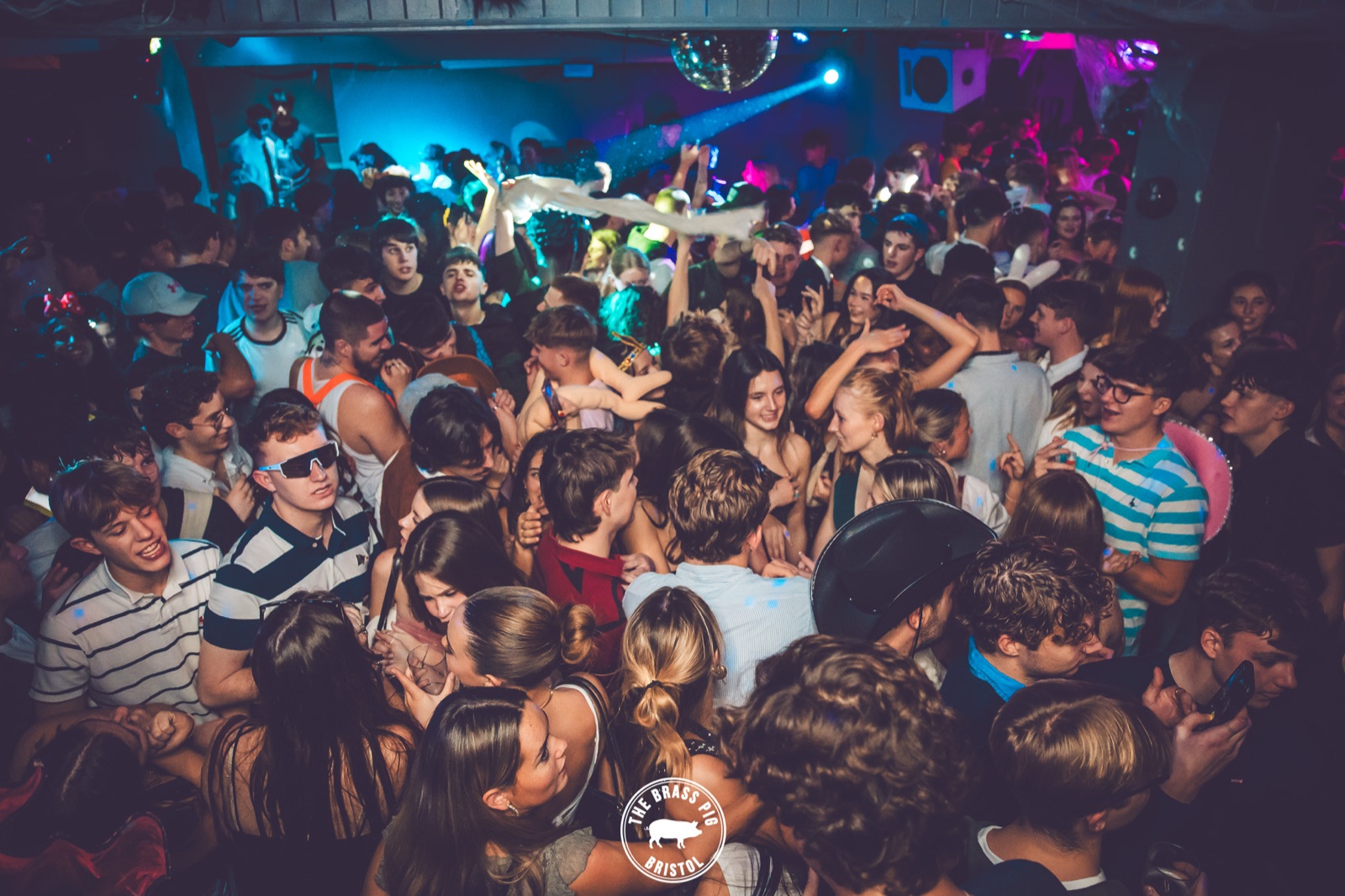 A packed dance floor under neon light at The Brass Pig, Bristol